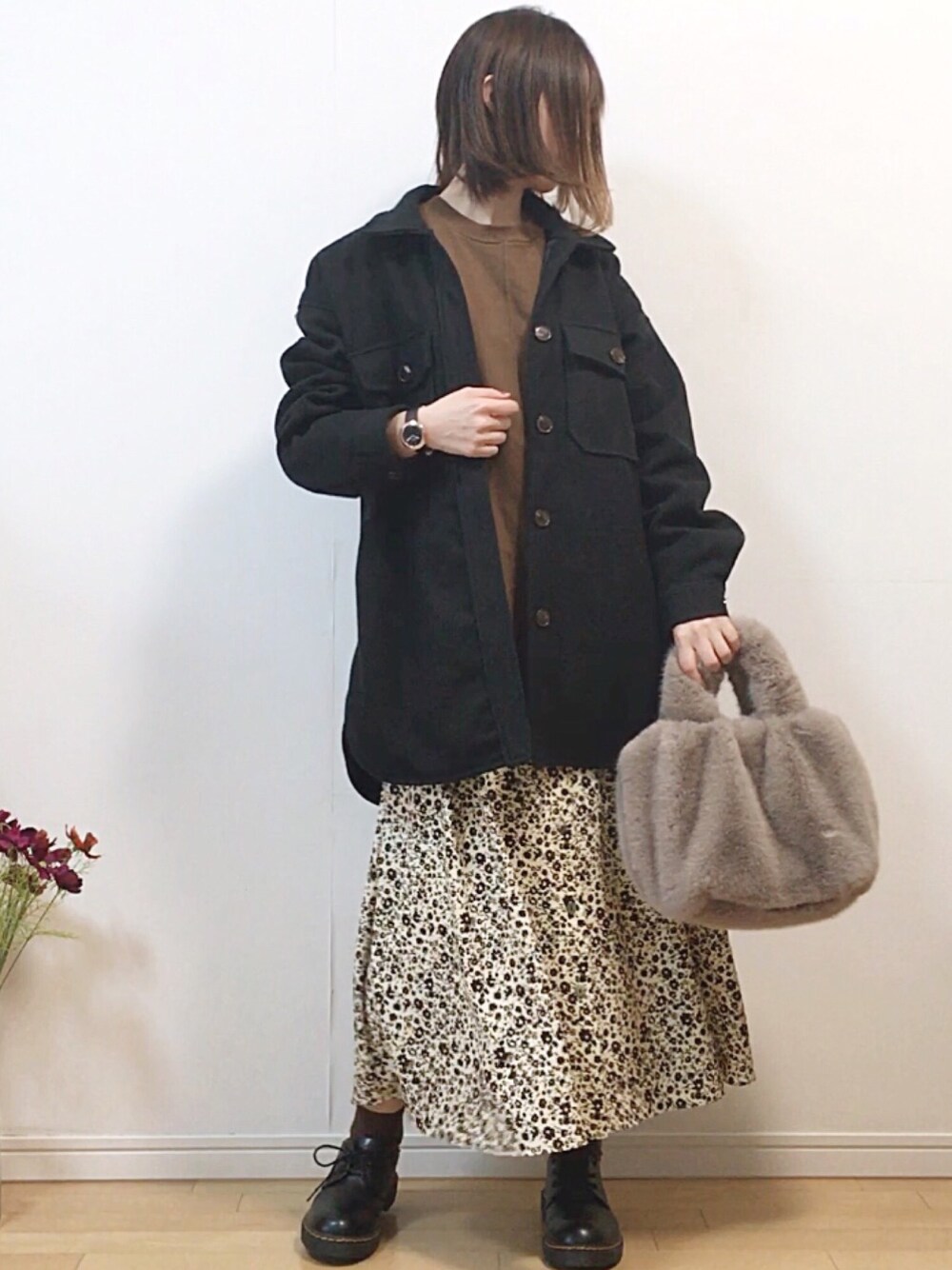 ブラック系のカバーオール、ブラウン系のTシャツ/カットソー、ホワイト系のスカートを着用したレディースの冬コーディネートの1枚目の写真