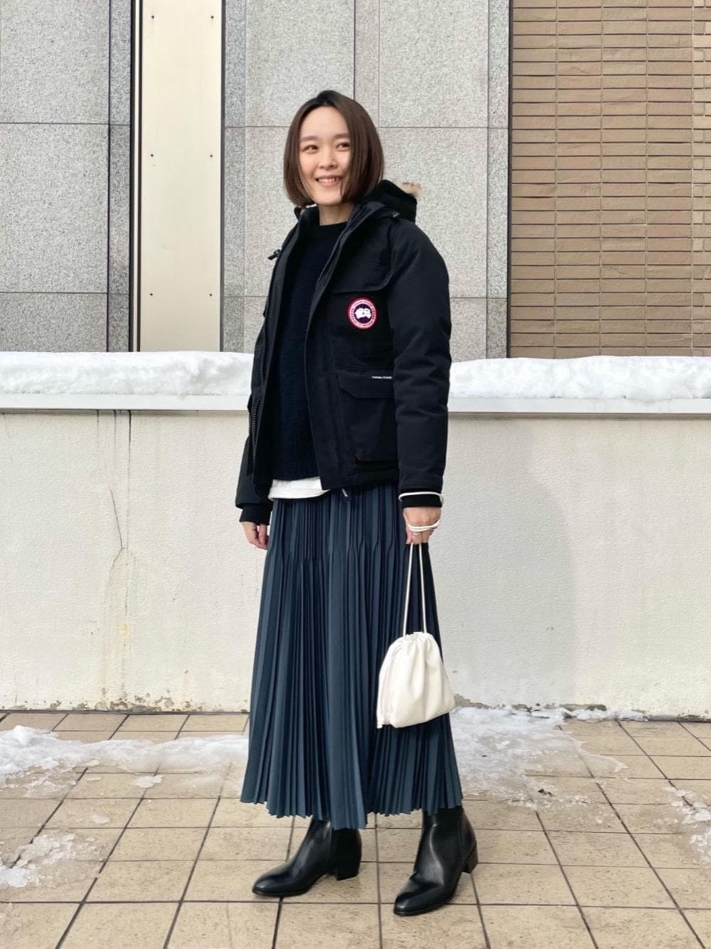 「ニット、ダウンジャケット、冬コーデ、プリーツスカート、ミニバッグ、オデットエオディール、Boots styling、Skirt style、休日すたいる、ぶーつ」｜「ODETTE E ODILEの＜ESLOW(エスロー)＞ DRAWSTRING BAG（ショルダーバッグ、ホワイト系）」を使った、伊藤　オデット エ オディール スタッフさん（レディース・164cm）の冬コーディネートの1枚目の写真