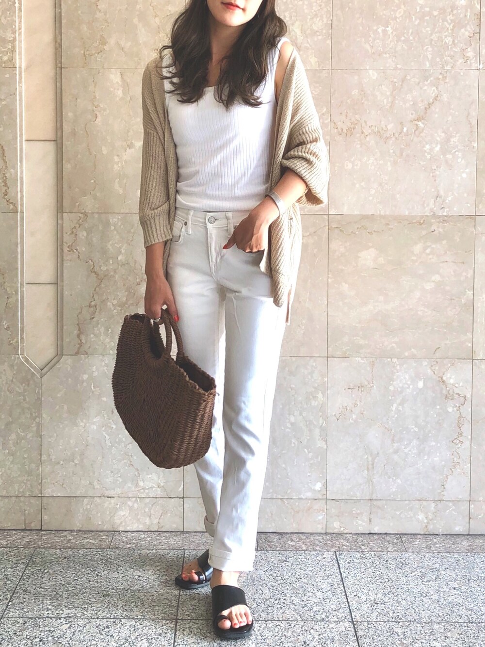 ホワイト系のデニムパンツ、ベージュ系のカーディガン/ボレロ、ブラウン系のかごバッグを着用したレディースの夏コーディネートの1枚目の写真