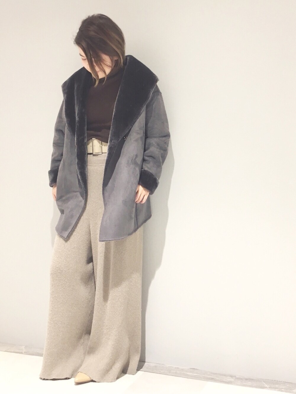 グレー系のムートンコート、ブラウン系のニット/セーター、ベージュ系のその他パンツを着用したレディースの秋コーディネートの1枚目の写真