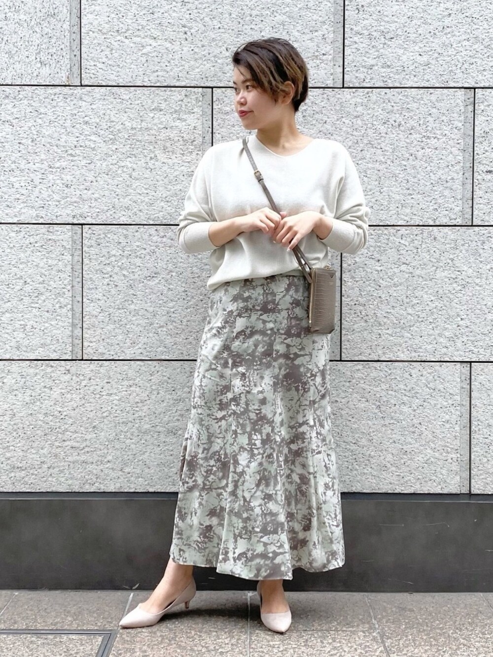 ホワイト系のニット/セーター、グリーン系のスカート、ピンク系のパンプスを着用したレディースの冬コーディネートの1枚目の写真