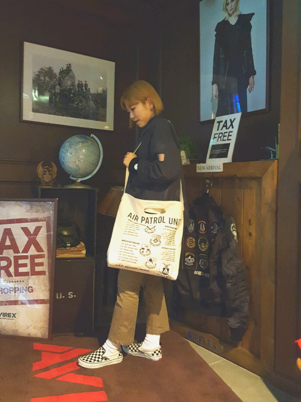 グレー系のミリタリージャケット、ブラック系のトートバッグ、グリーン系のカーゴパンツを着用したレディースの春コーディネートの1枚目の写真