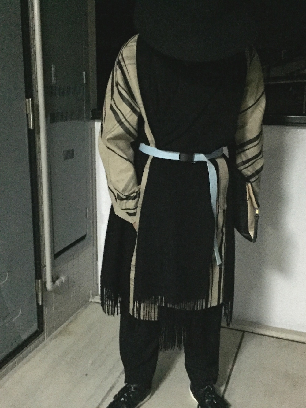 ベージュ系のその他アウター、ベージュ系のクラッチバッグ、ブラック系のスニーカーを着用したメンズの冬コーディネートの1枚目の写真