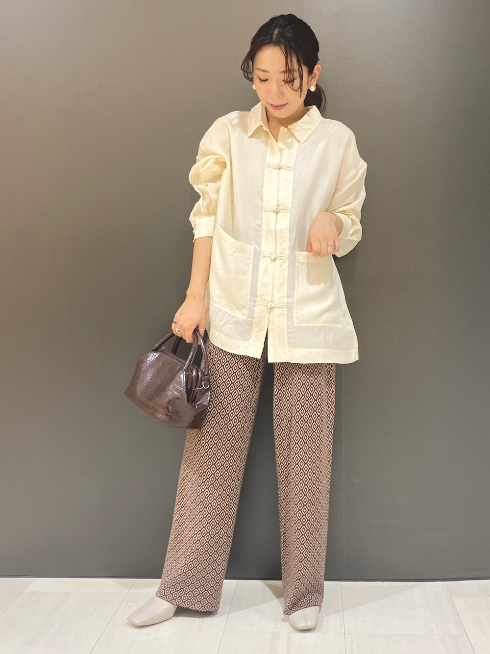ホワイト系のシャツ/ブラウス、ブラウン系のショルダーバッグ、ブラウン系のパンツを着用したレディースの夏コーディネートの1枚目の写真