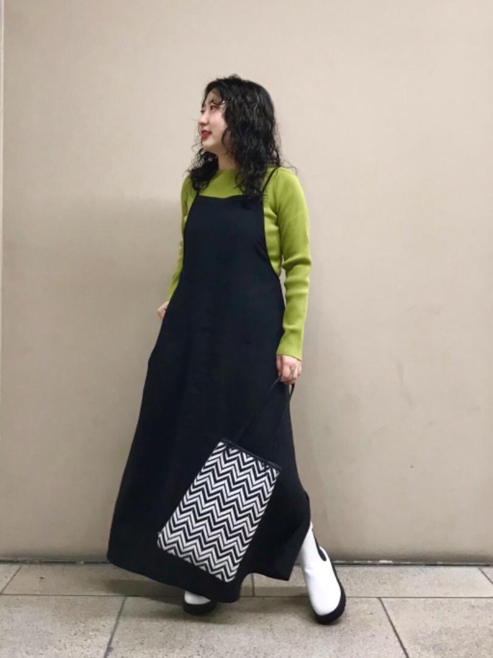 ホワイト系のレインシューズ、ブラック系のショルダーバッグ、グリーン系のニット/セーターを着用したレディースの秋コーディネートの1枚目の写真