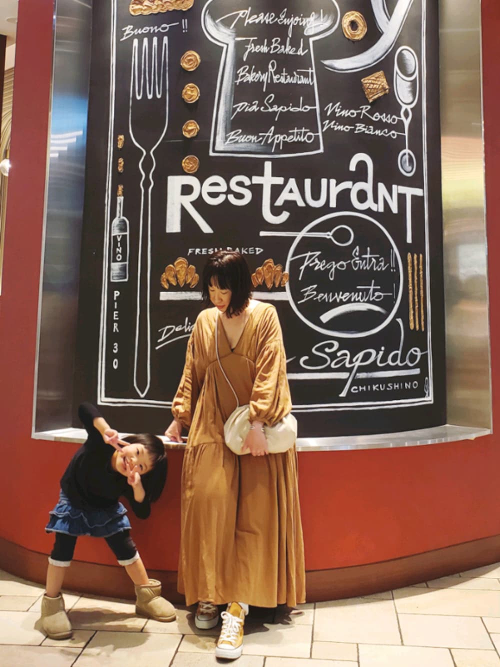 ホワイト系のハンドバッグ、ブラック系のスニーカー、ブラウン系のワンピースを着用したレディースの冬コーディネートの1枚目の写真