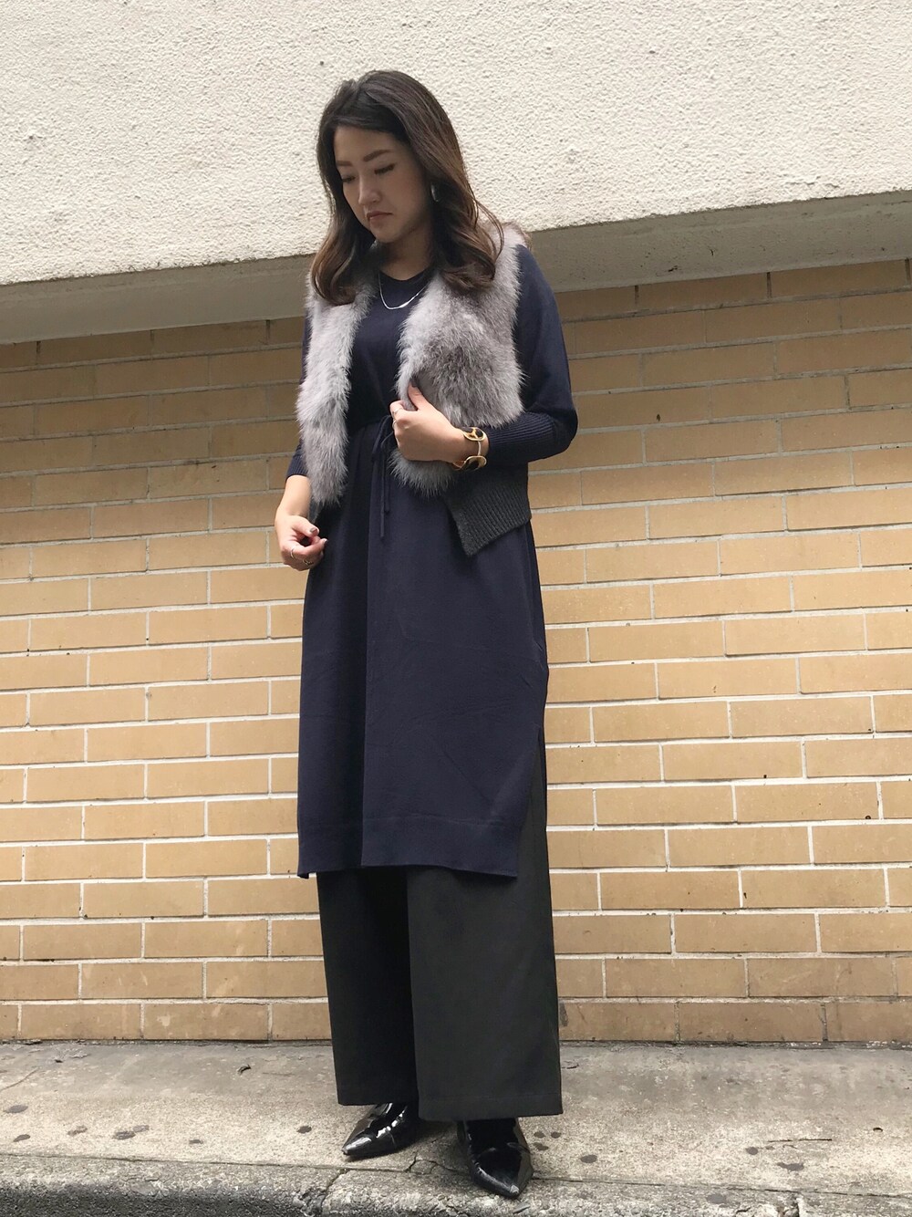 グレー系のベスト、ブルー系のワンピースを着用したレディースの秋コーディネートの1枚目の写真