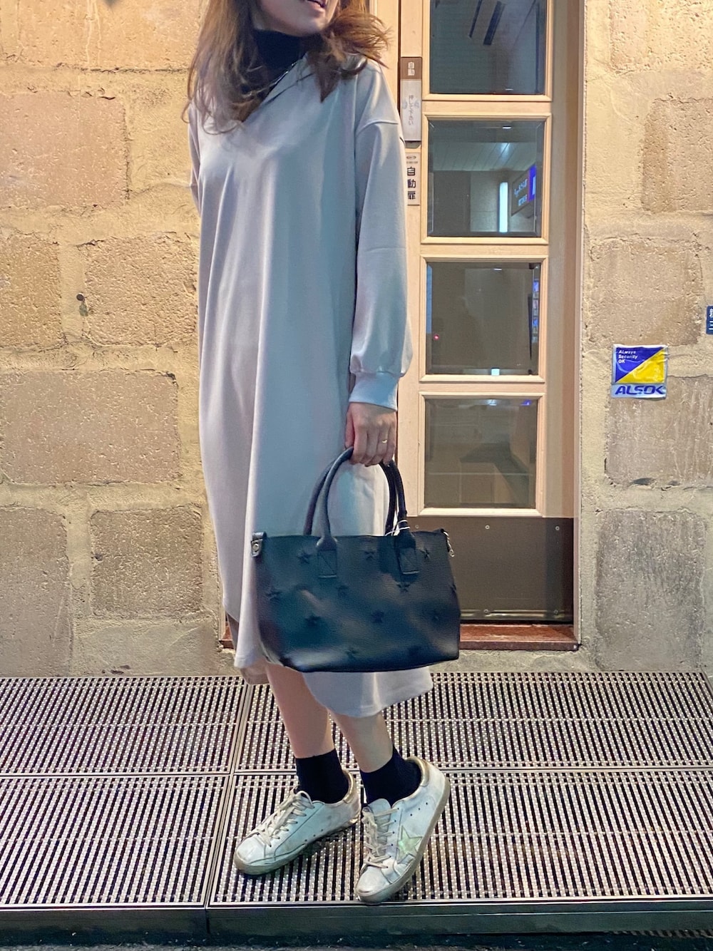 ブラック系のトートバッグ、ホワイト系のスニーカー、グレー系のワンピースを着用したレディースの冬コーディネートの1枚目の写真