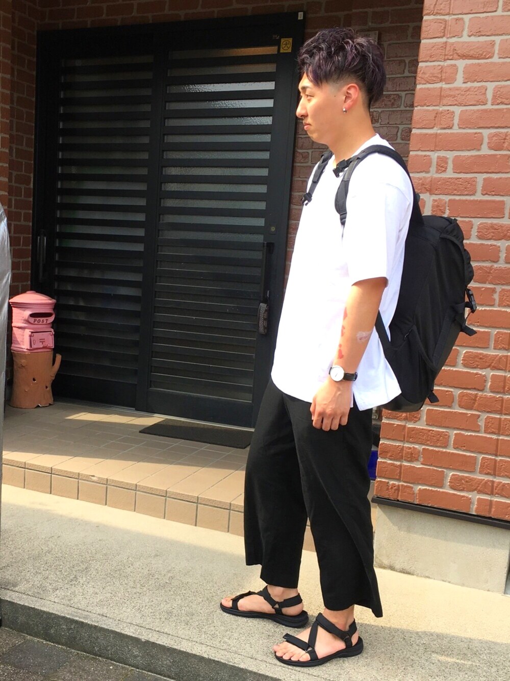 ブラック系のサンダル、ブラック系のバックパック/リュック、ブラック系のスラックスを着用したメンズの春コーディネートの1枚目の写真