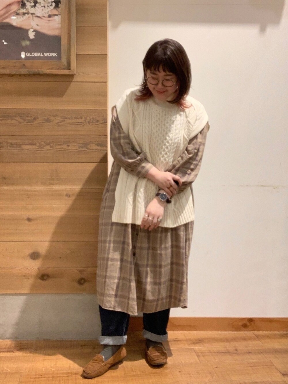 ホワイト系のベスト、ベージュ系のワンピース、ブルー系のデニムパンツを着用したレディースの秋コーディネートの1枚目の写真