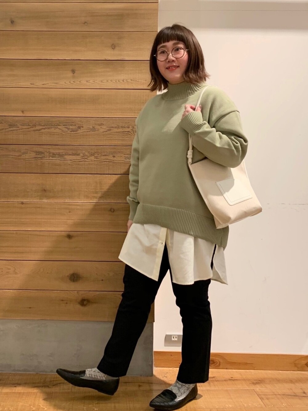 ホワイト系のシャツ/ブラウス、グリーン系のニット/セーター、ホワイト系のショルダーバッグを着用したレディースの冬コーディネートの1枚目の写真