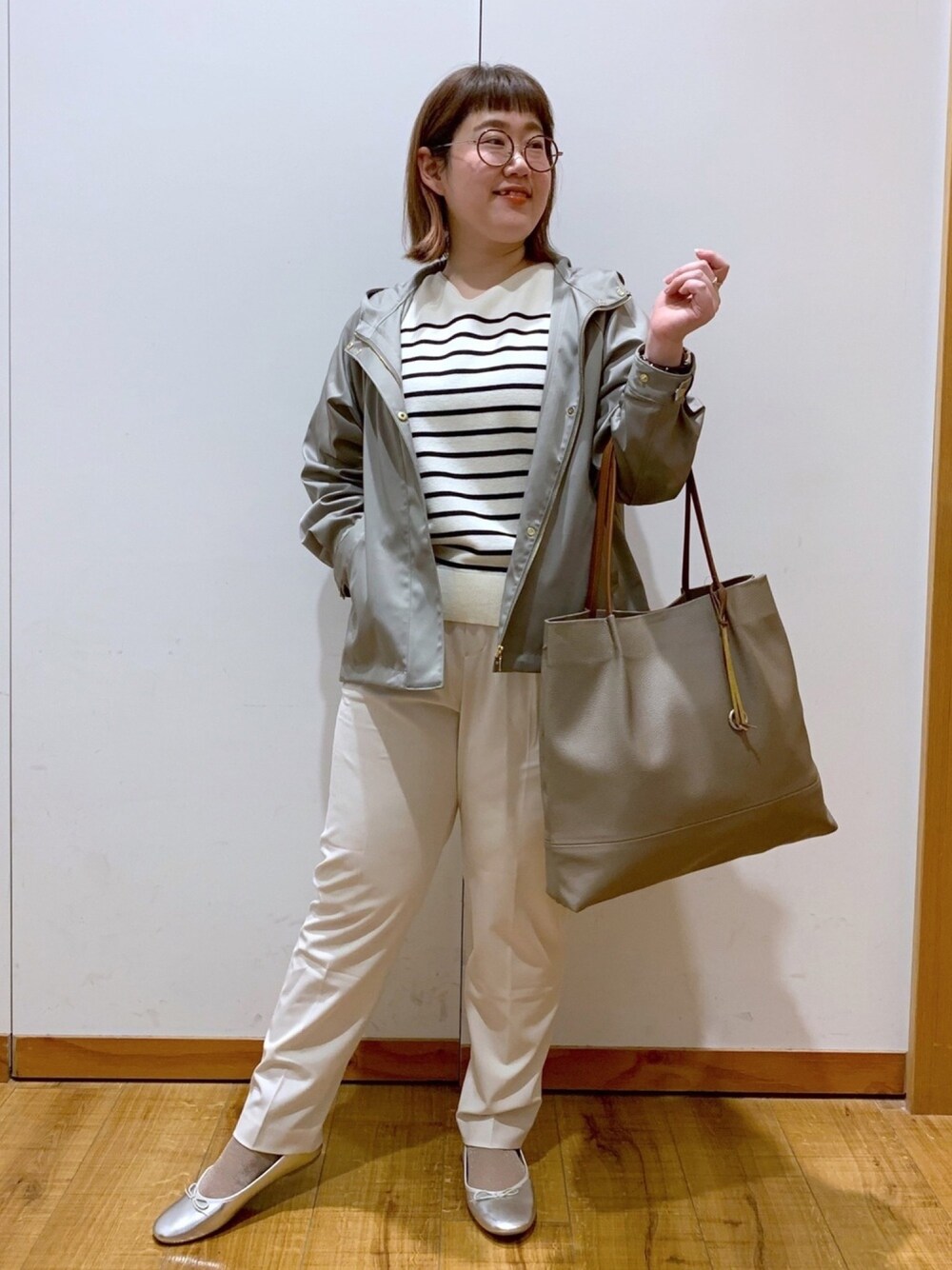 グリーン系のブルゾン、ブルー系のニット/セーター、ベージュ系のトートバッグを着用したレディースの冬コーディネートの1枚目の写真