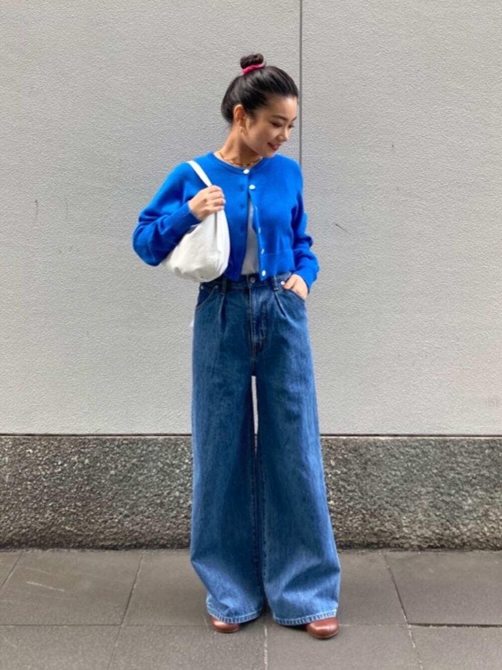 ホワイト系のショルダーバッグ、ブラウン系のサンダル、ブルー系のデニムパンツを着用したレディースの冬コーディネートの1枚目の写真