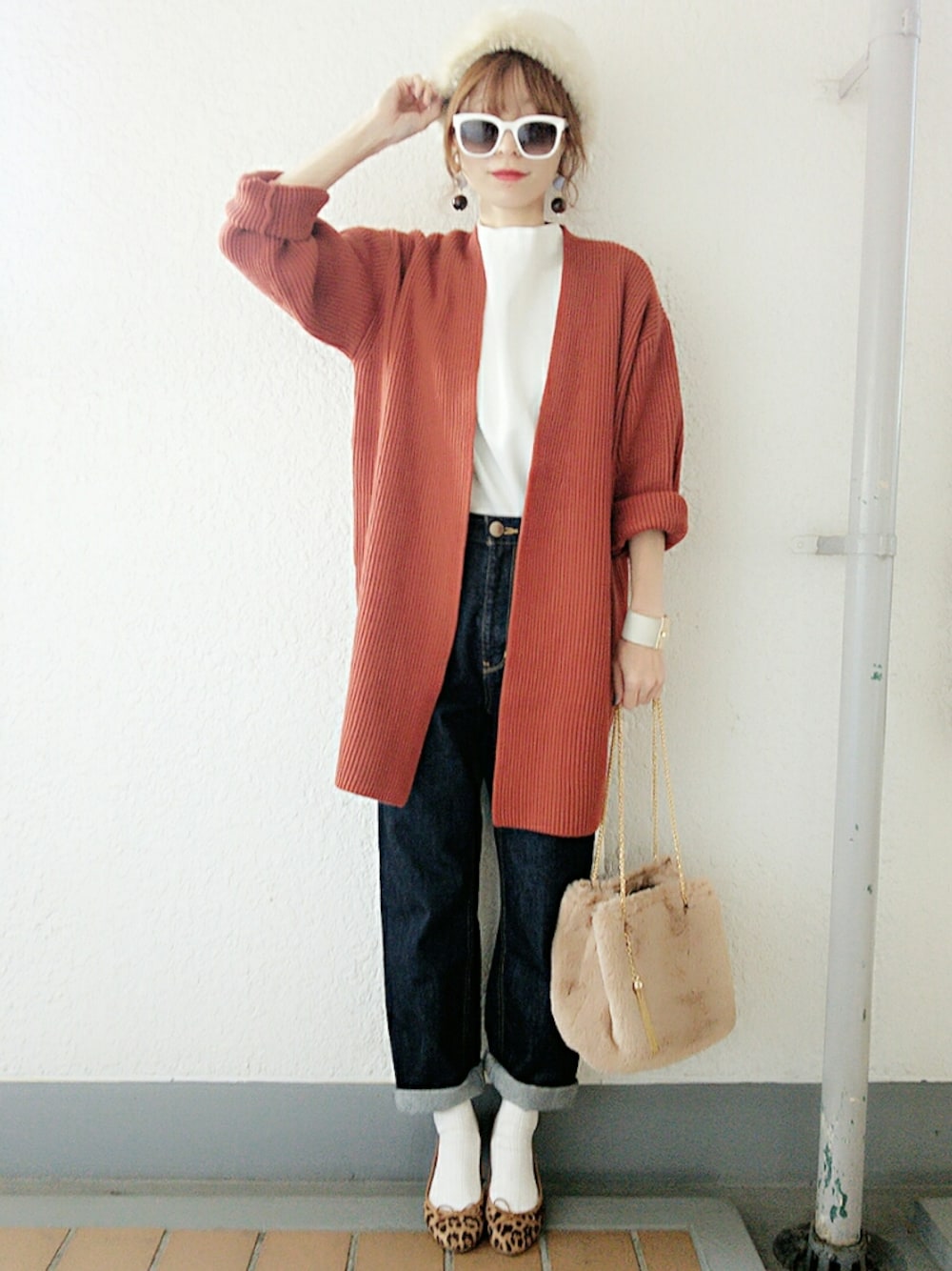 オレンジ系のカーディガン/ボレロ、ホワイト系のTシャツ/カットソー、ブルー系のデニムパンツを着用したレディースの冬コーディネートの1枚目の写真