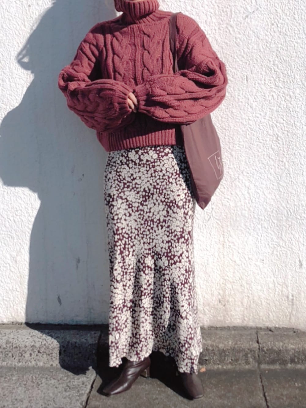 ピンク系のニット/セーター、ブラウン系のスカート、ブラウン系のブーツを着用したレディースの秋コーディネートの1枚目の写真