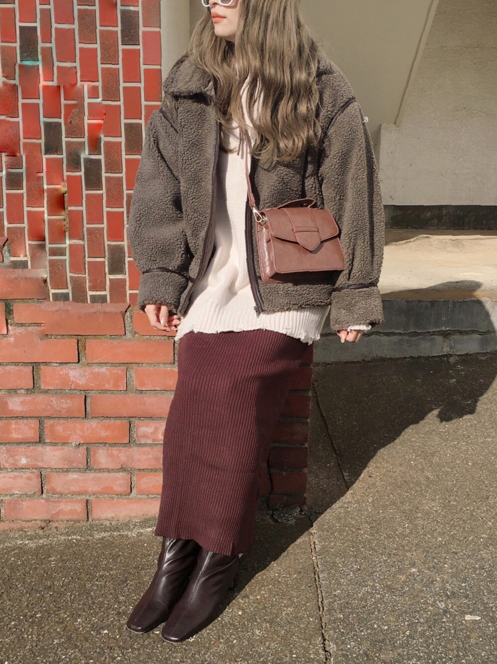 ブラウン系のその他アウター、ホワイト系のニット/セーター、ブラウン系のスカートを着用したレディースの冬コーディネートの1枚目の写真
