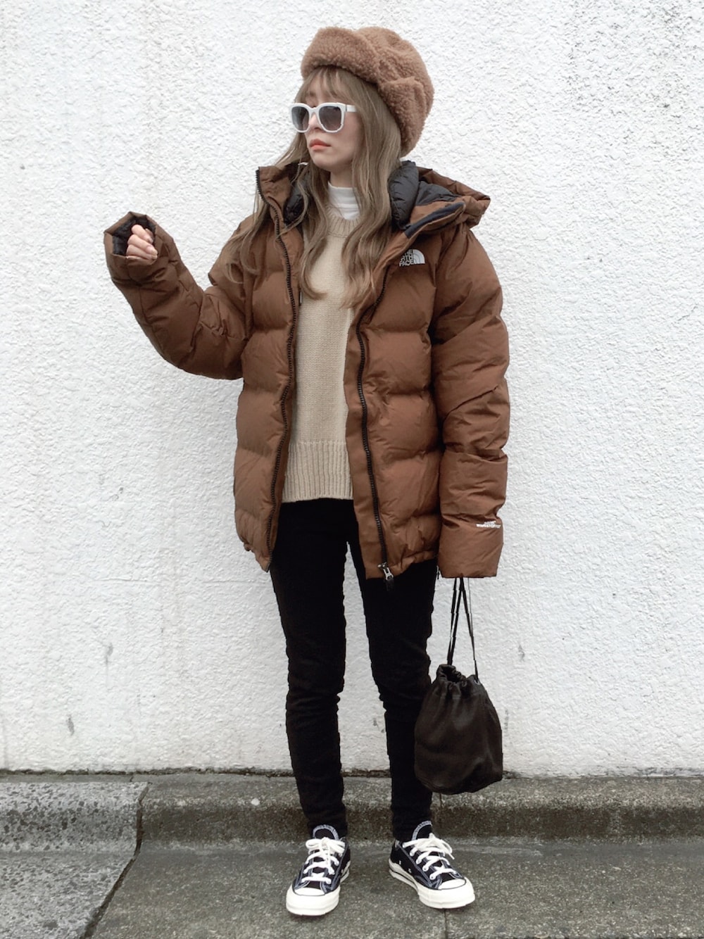 ホワイト系のTシャツ/カットソー、ブラウン系のダウンジャケット/コート、ベージュ系のニット/セーターを着用したレディースの冬コーディネートの1枚目の写真