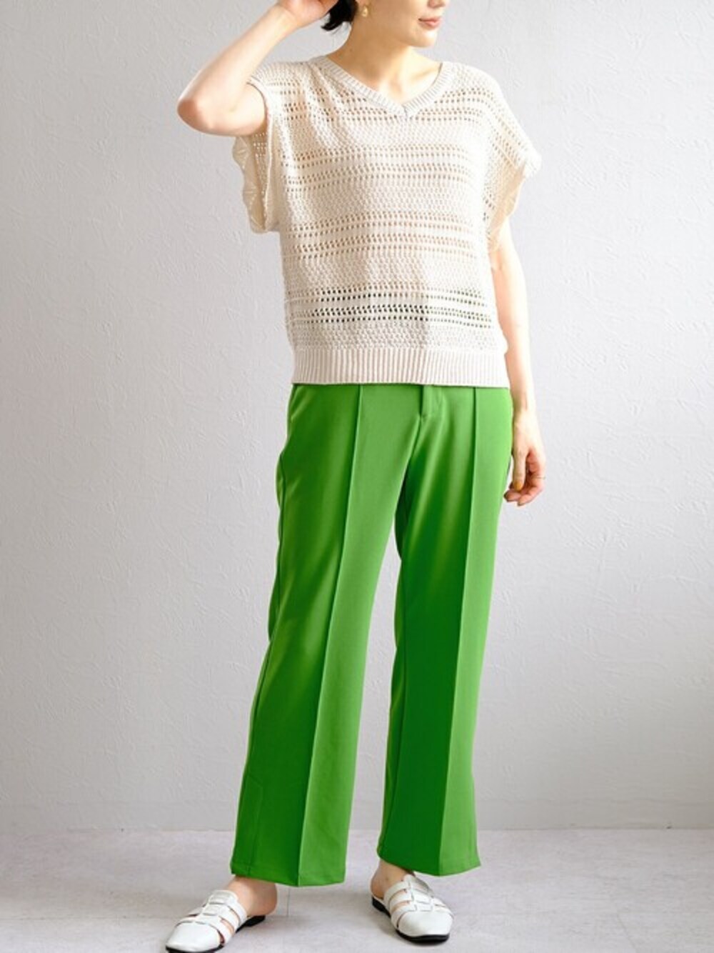 ベージュ系のニット/セーター、グリーン系のスラックスを着用したレディースの夏コーディネートの1枚目の写真