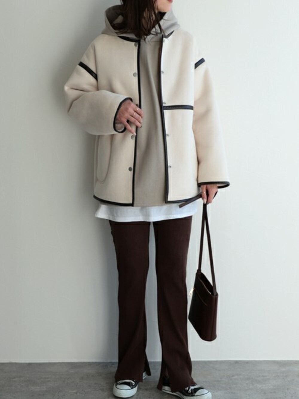 ベージュ系のパーカー、ホワイト系のノーカラーコートを着用したレディースの冬コーディネートの1枚目の写真
