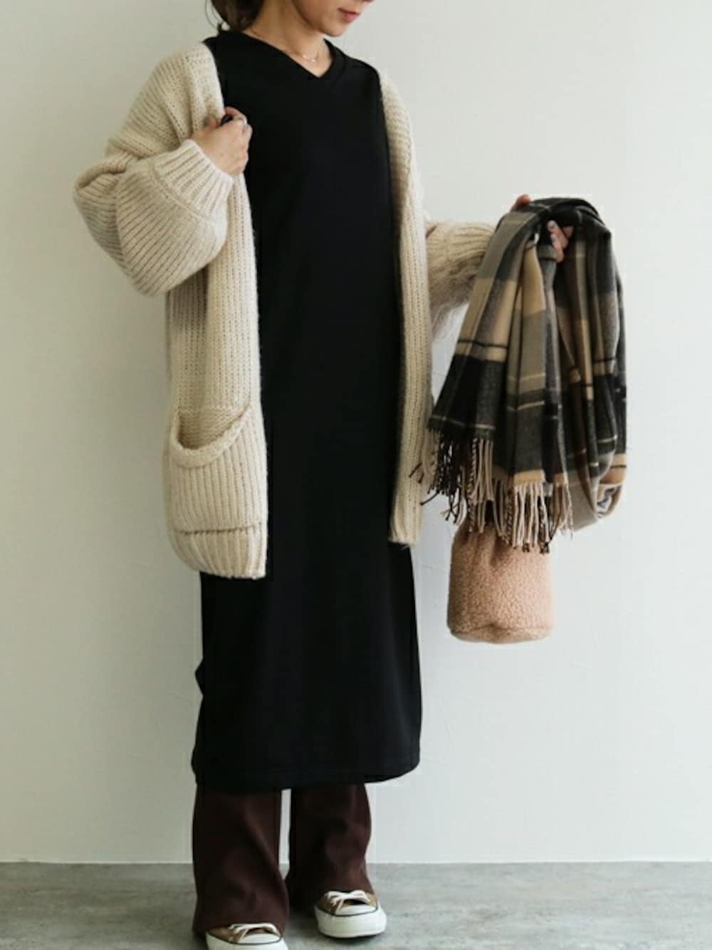 ブラック系のワンピース、ホワイト系のカーディガン/ボレロを着用したレディースの冬コーディネートの1枚目の写真