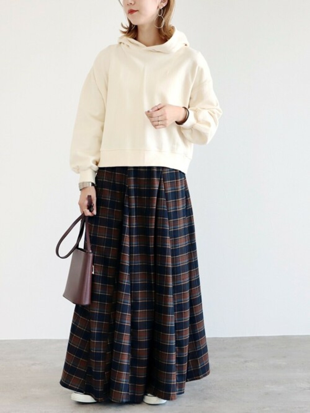 ホワイト系のパーカー、パープル系のスカートを着用したレディースの秋コーディネートの1枚目の写真