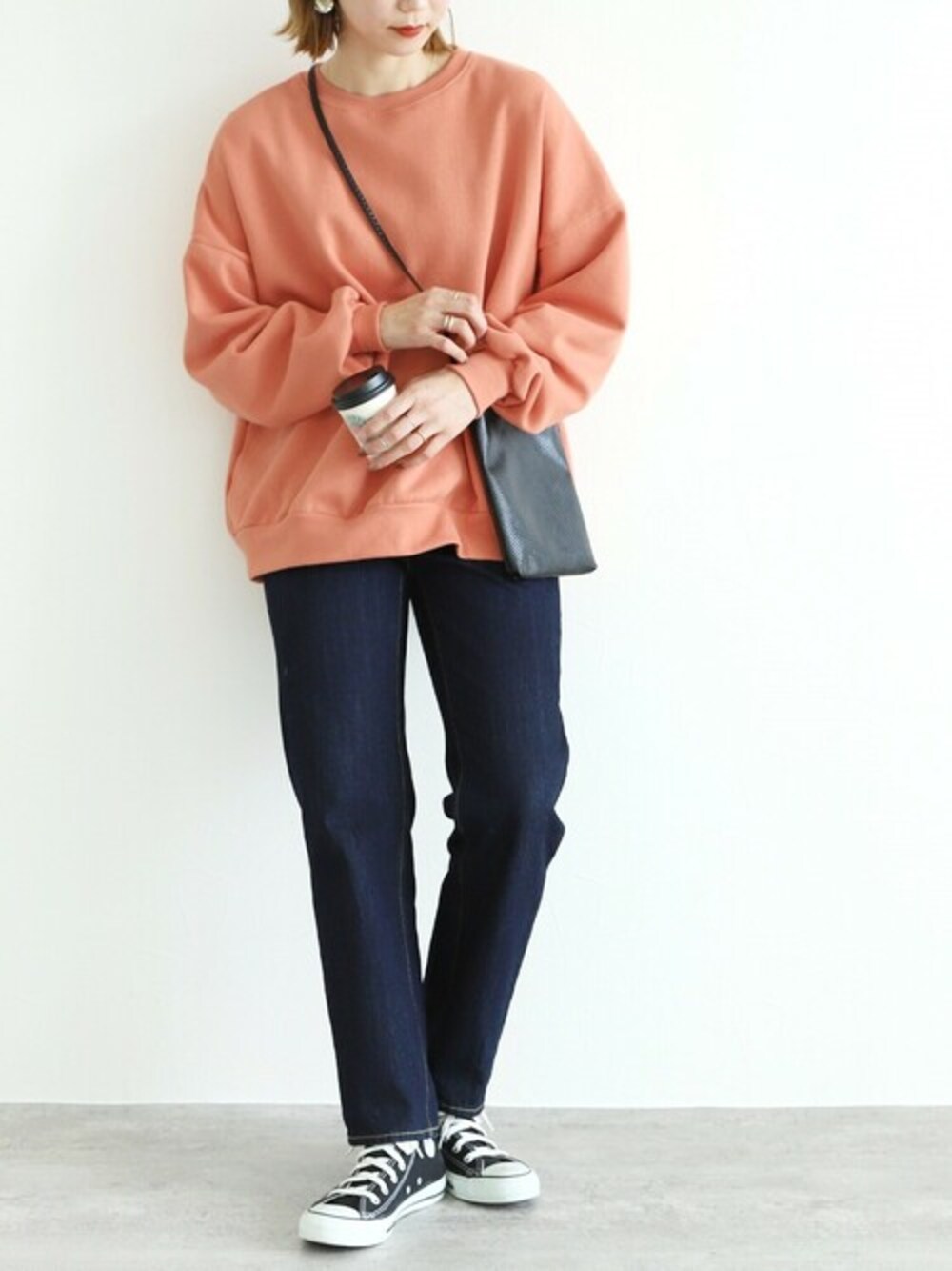 オレンジ系のスウェットを着用したレディースの秋コーディネートの1枚目の写真