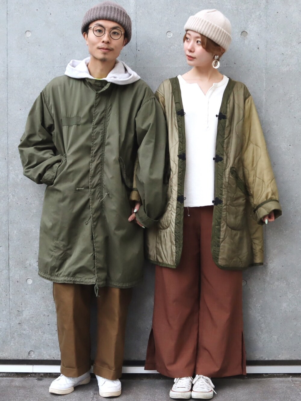 グリーン系のモッズコート、ブラウン系のパンツ、ホワイト系のスニーカーを着用したメンズの春コーディネートの1枚目の写真