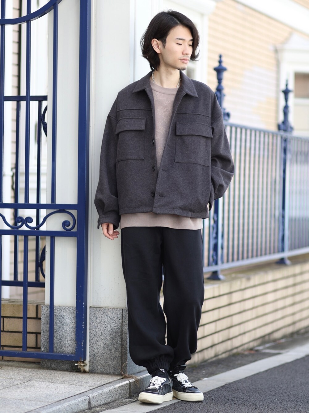 グレー系のブルゾン、ベージュ系のニット/セーター、ブラック系のスニーカーを着用したメンズの秋コーディネートの1枚目の写真