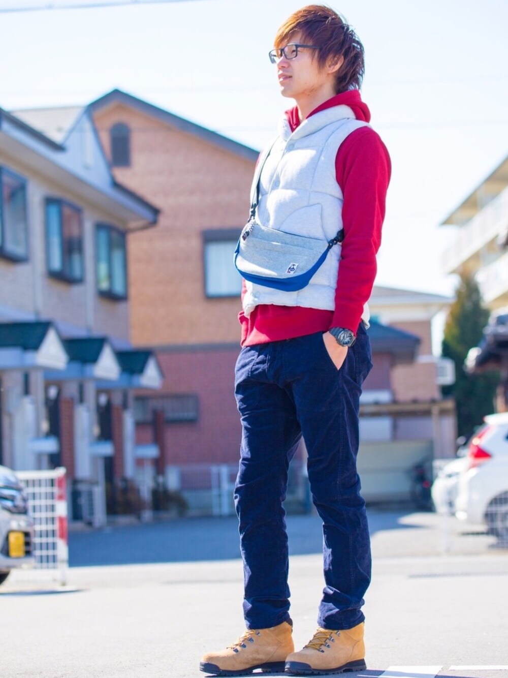 レッド系のパーカー、ベージュ系のダウンベスト、グレー系のショルダーバッグを着用したメンズの冬コーディネートの1枚目の写真