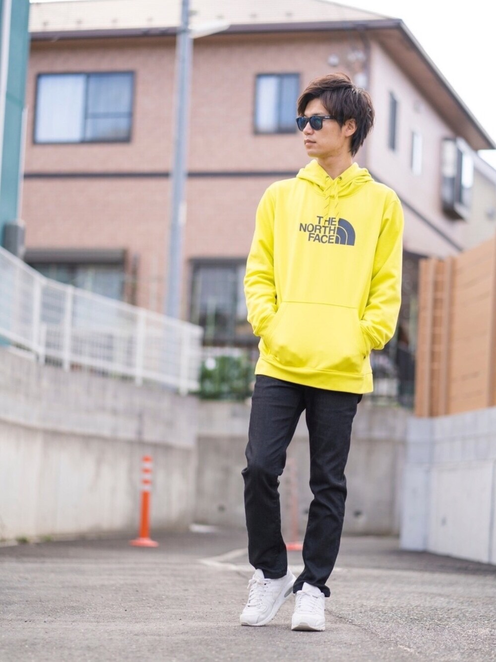 イエロー系のパーカー、ホワイト系のスニーカー、ブラック系のパンツを着用したメンズの冬コーディネートの1枚目の写真