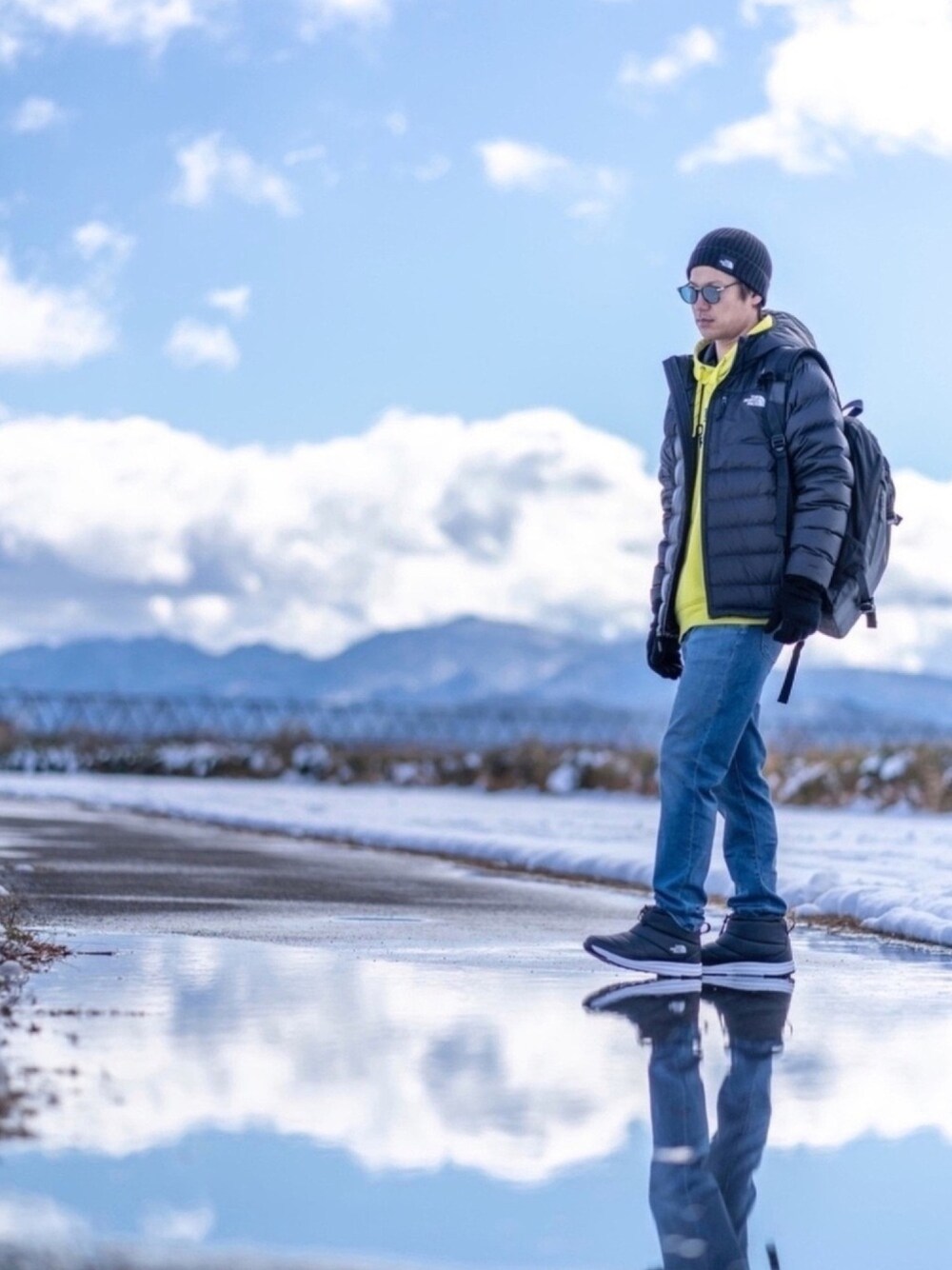 イエロー系のパーカー、ブラック系のダウンジャケット/コート、ブラック系のバックパック/リュックを着用したメンズの冬コーディネートの1枚目の写真