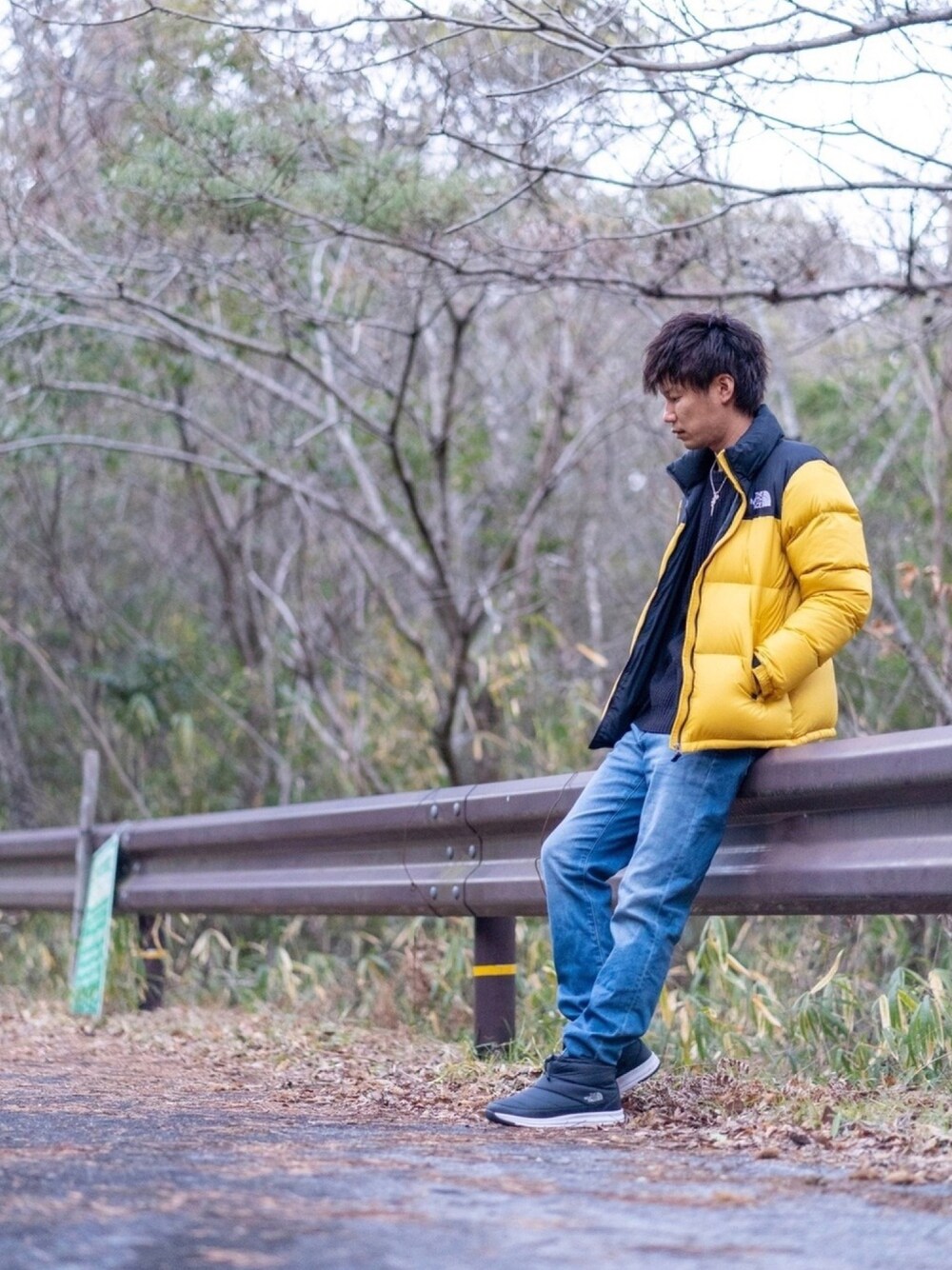 イエロー系のダウンジャケット/コート、ブラック系のニット/セーター、ブルー系のデニムパンツを着用したメンズの冬コーディネートの1枚目の写真