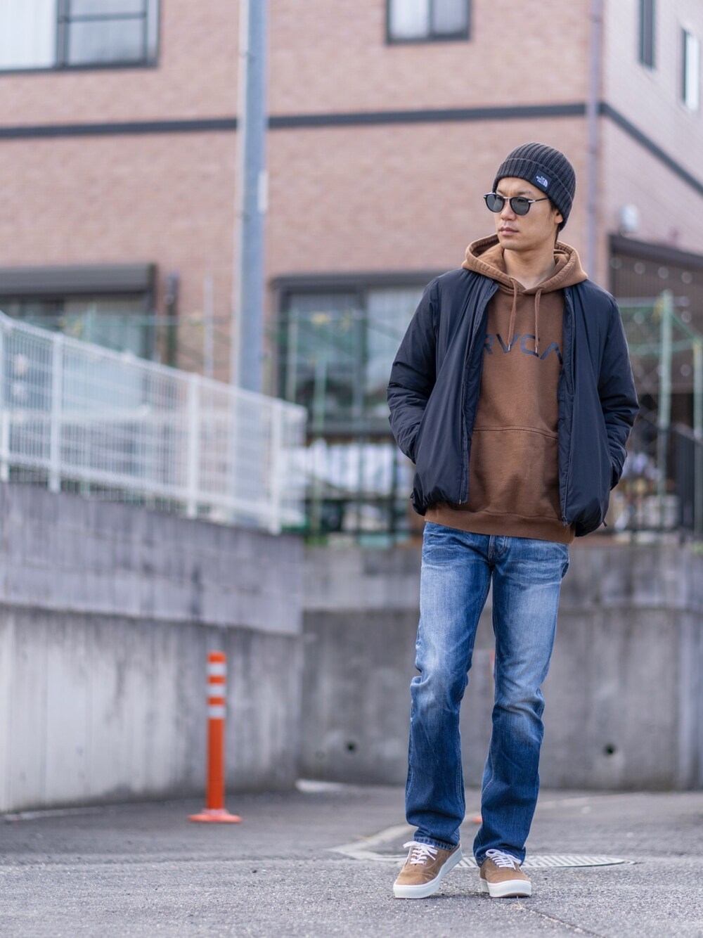 ブラック系のダウンジャケット/コート、ブラウン系のパーカー、ブルー系のデニムパンツを着用したメンズの冬コーディネートの1枚目の写真