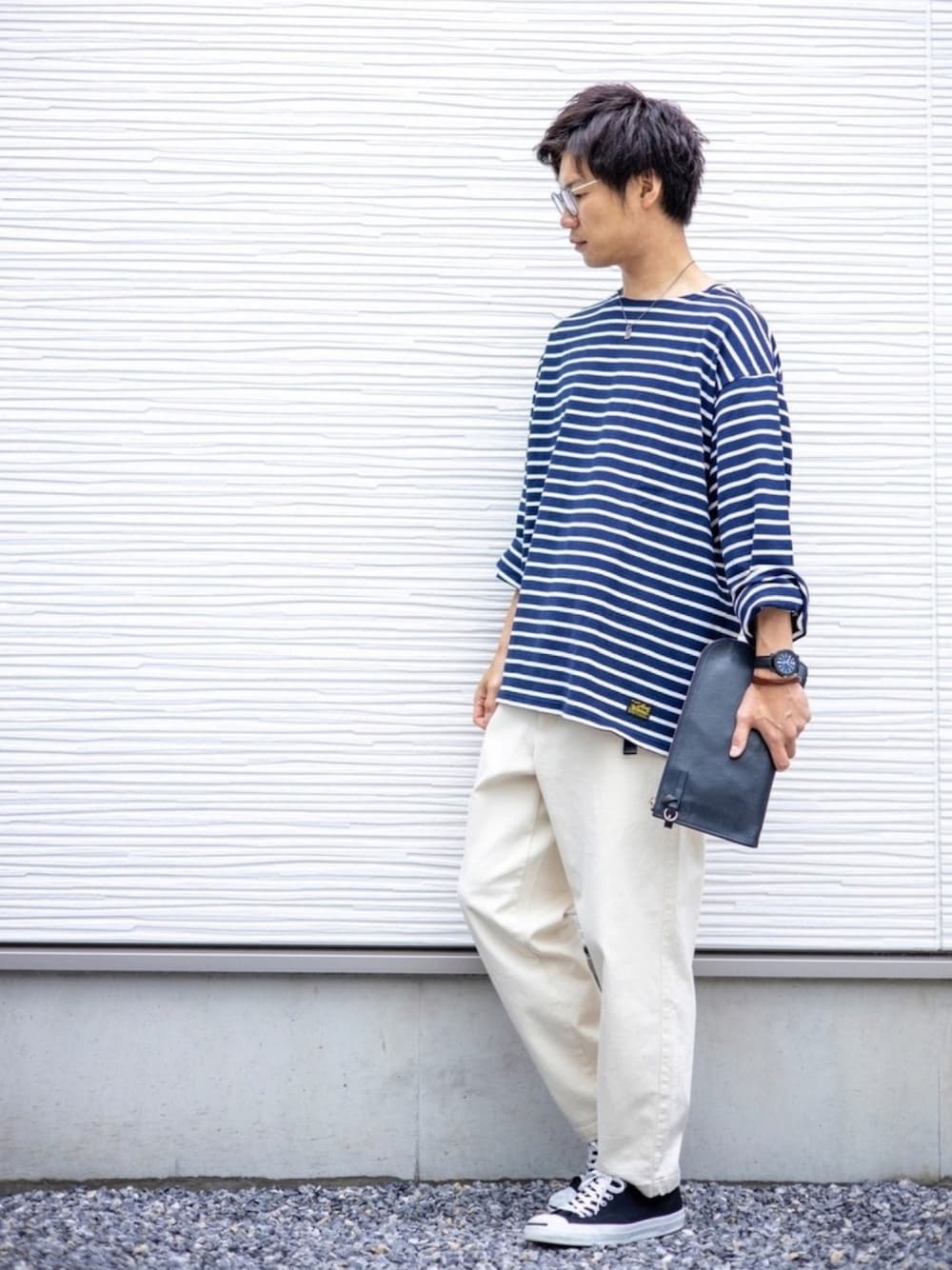 ブルー系のTシャツ/カットソー、ブルー系のクラッチバッグ、ホワイト系のデニムパンツを着用したメンズの春コーディネートの1枚目の写真