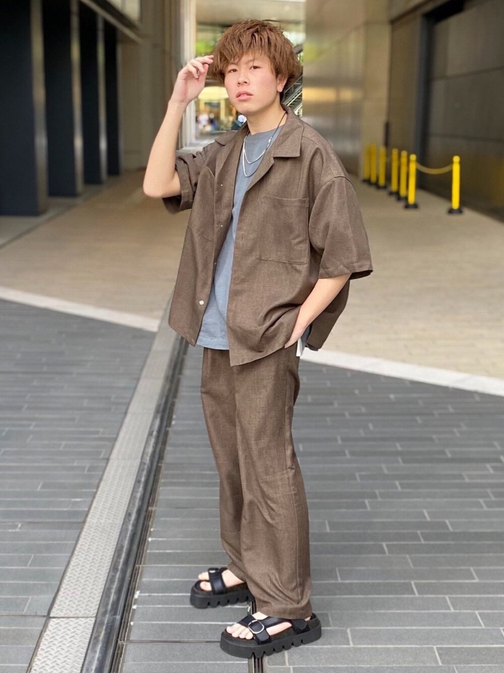 ブラウン系のセットアップ、グレー系のTシャツ/カットソー、ブラック系のサンダルを着用したメンズの春コーディネートの1枚目の写真