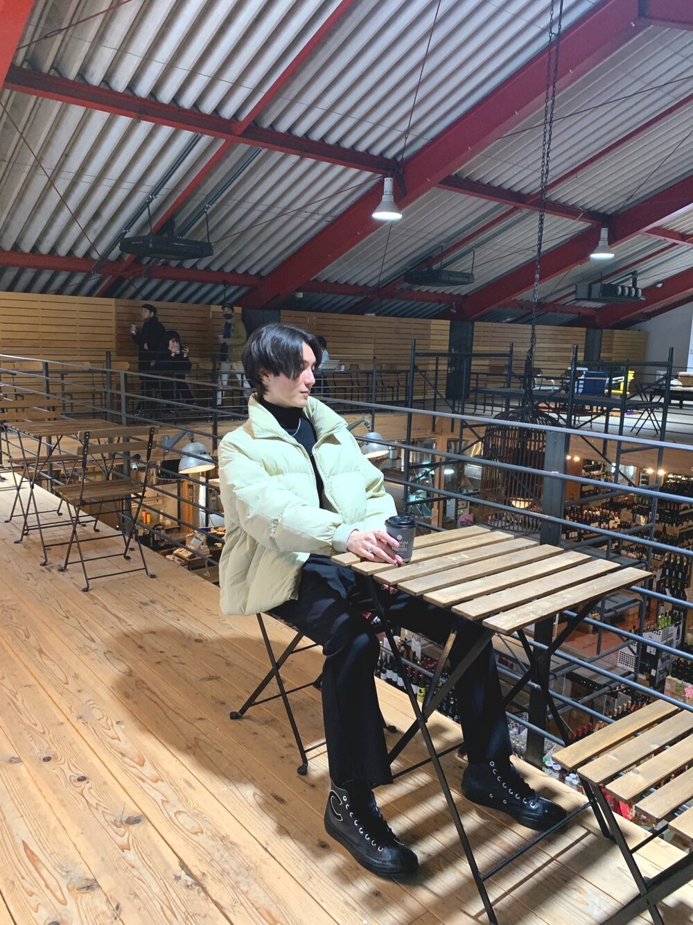 ベージュ系のダウンジャケット/コート、ブラック系のニット/セーター、ブラック系のスラックスを着用したメンズの春コーディネートの1枚目の写真