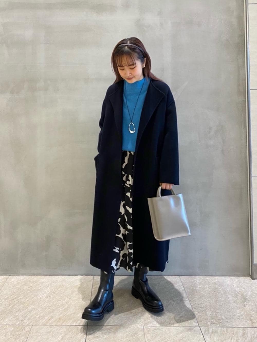 ブルー系のノーカラーコート、ブラック系のブーツ、ブルー系のニット/セーターを着用したレディースの秋コーディネートの1枚目の写真