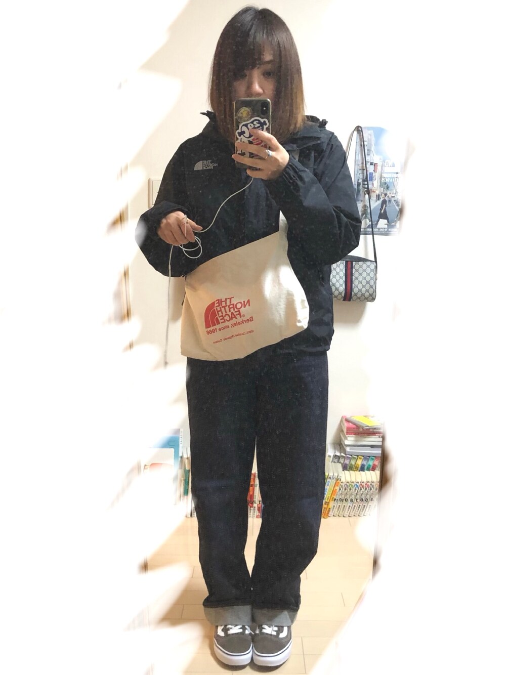 ブラック系のマウンテンパーカー、ホワイト系のショルダーバッグ、ブルー系のデニムパンツを着用したレディースの春コーディネートの1枚目の写真