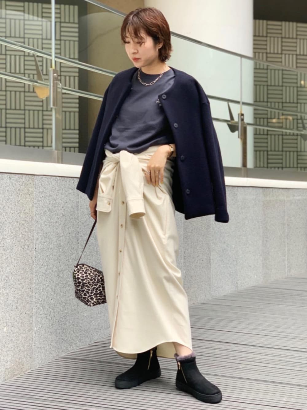 ブルー系のノーカラーコート、ベージュ系のワンピース、ブラック系のスニーカーを着用したレディースの秋コーディネートの1枚目の写真
