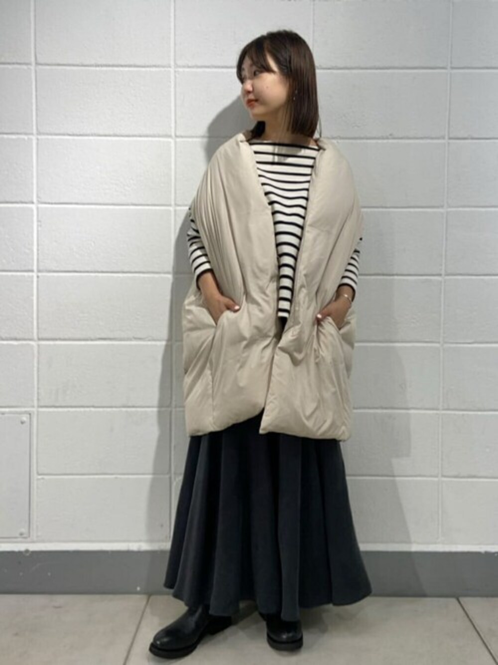 ホワイト系のダウンベスト、ホワイト系のTシャツ/カットソー、ブラック系のスカートを着用したレディースの夏コーディネートの1枚目の写真