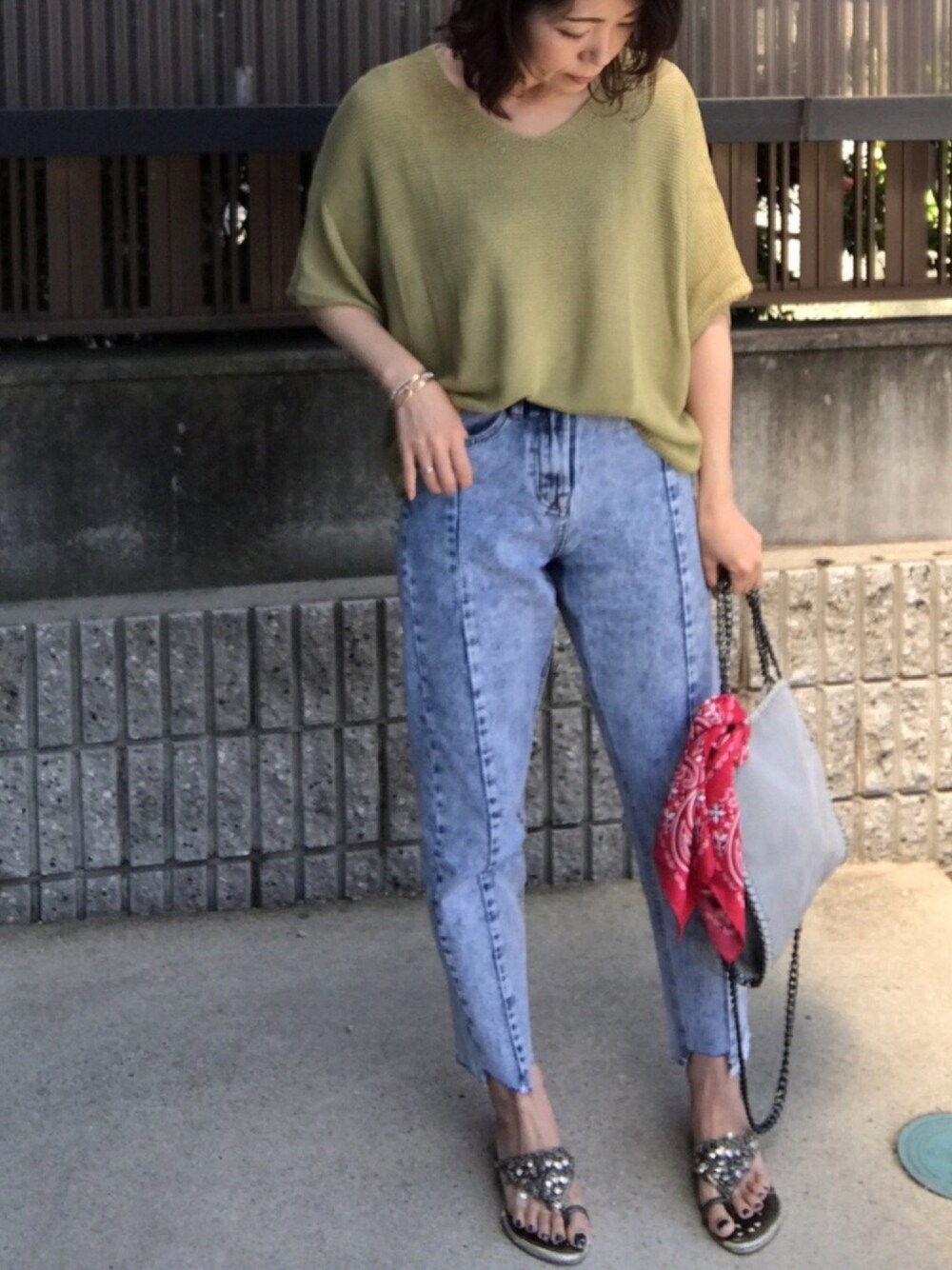 グリーン系のニット/セーター、ブルー系のデニムパンツ、グレー系のバッグを着用したレディースの春コーディネートの1枚目の写真