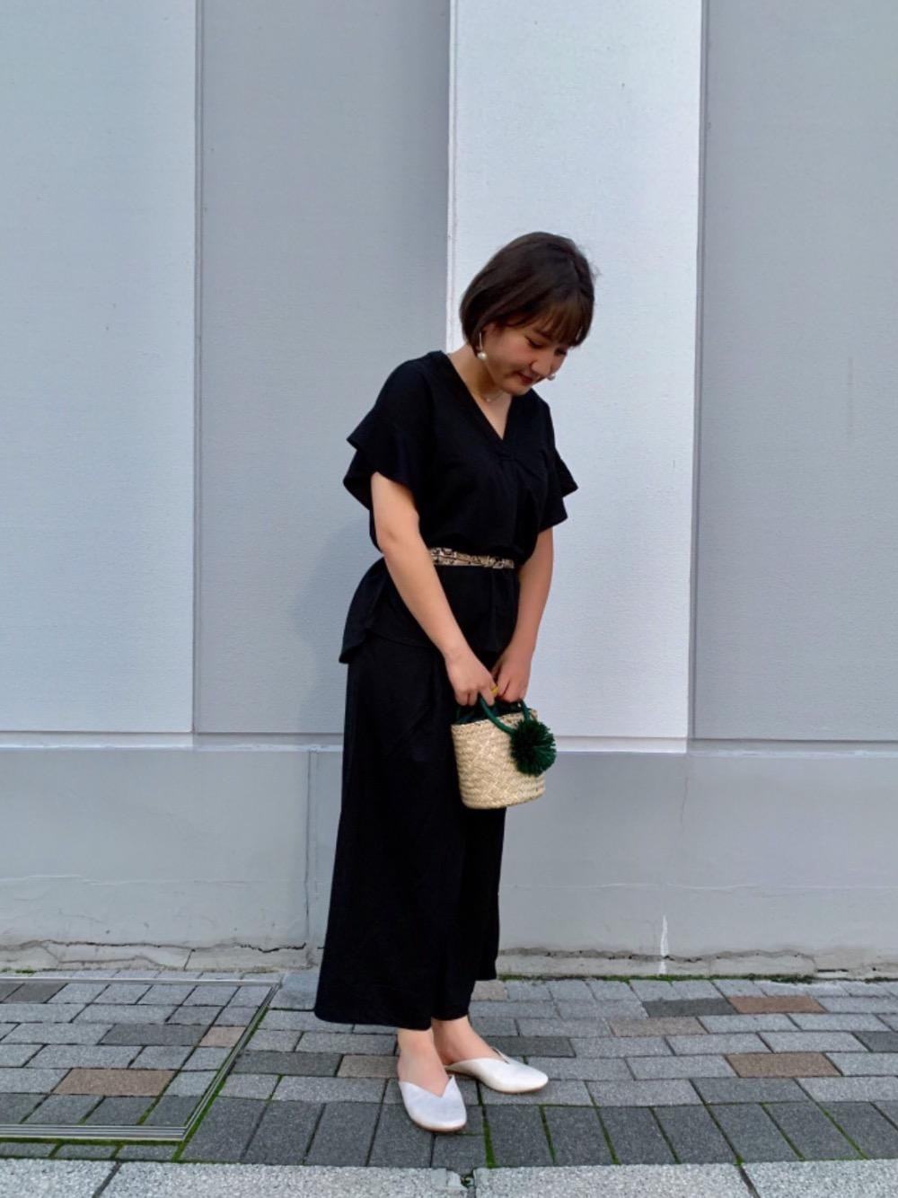 ベージュ系のサンダル、グリーン系のかごバッグ、ブラック系のシャツ/ブラウスを着用したレディースの夏コーディネートの1枚目の写真