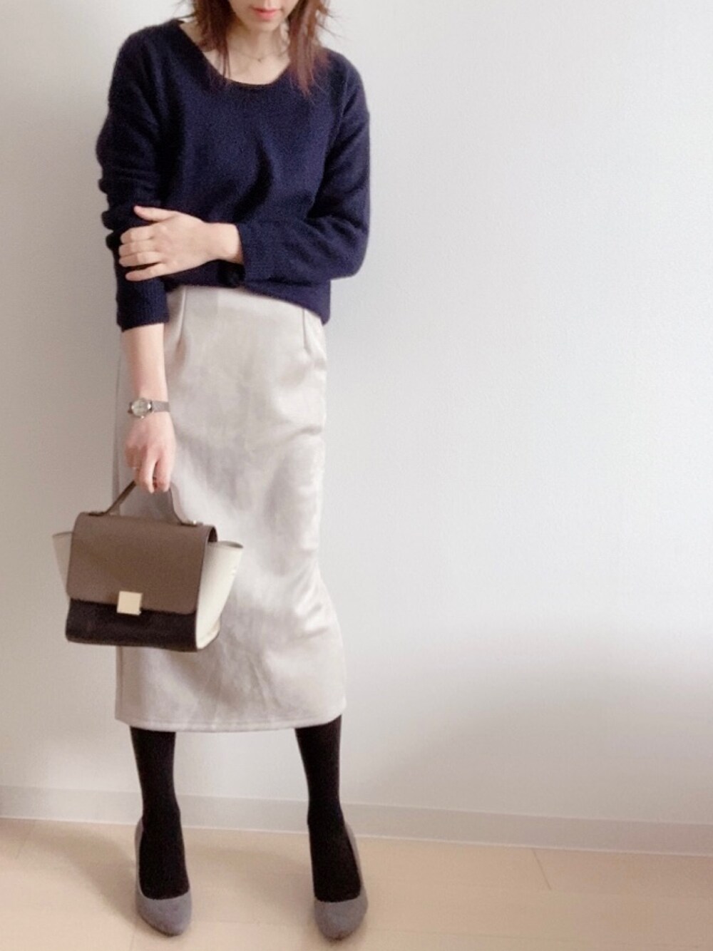 ベージュ系のスカート、ブラウン系のショルダーバッグ、ブルー系のニット/セーターを着用したレディースの冬コーディネートの1枚目の写真