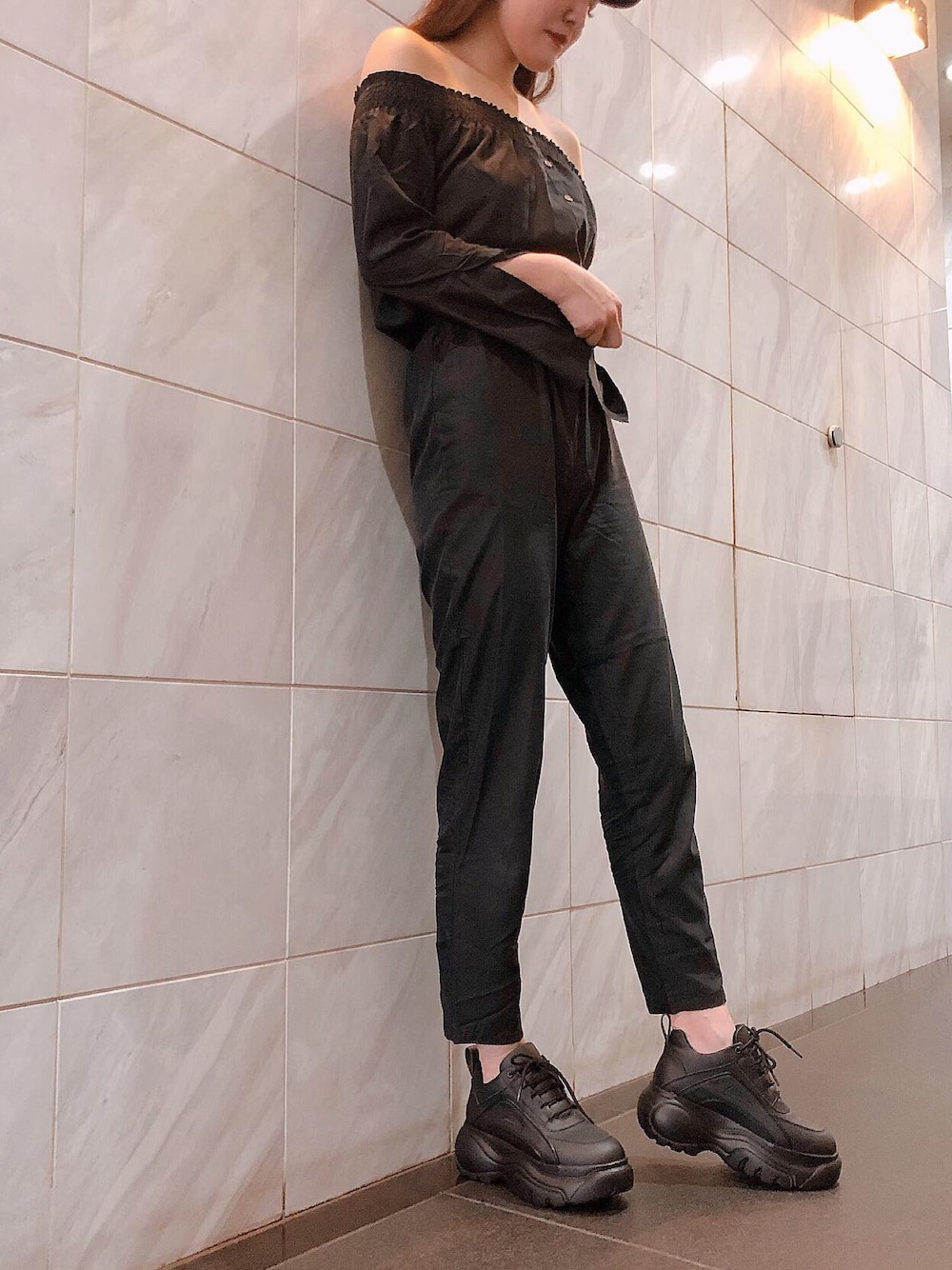 ブラック系のスニーカーを着用したレディースの秋コーディネートの1枚目の写真