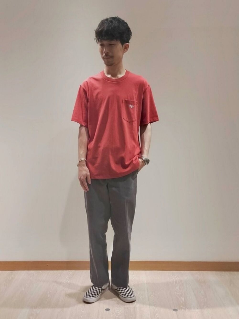 レッド系のTシャツ/カットソー、ホワイト系のスリッポン、グレー系のチノパンツを着用したメンズの夏コーディネートの1枚目の写真