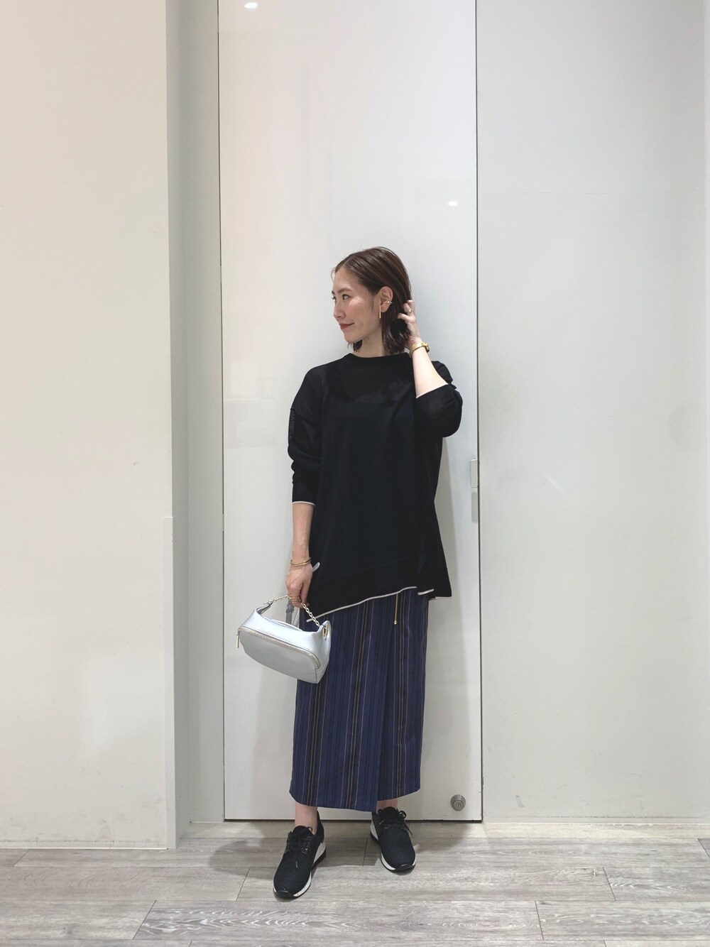 ブラック系のニット/セーター、ブルー系のスカート、シルバー系のボディバッグ/ウエストポーチを着用したレディースの夏コーディネートの1枚目の写真