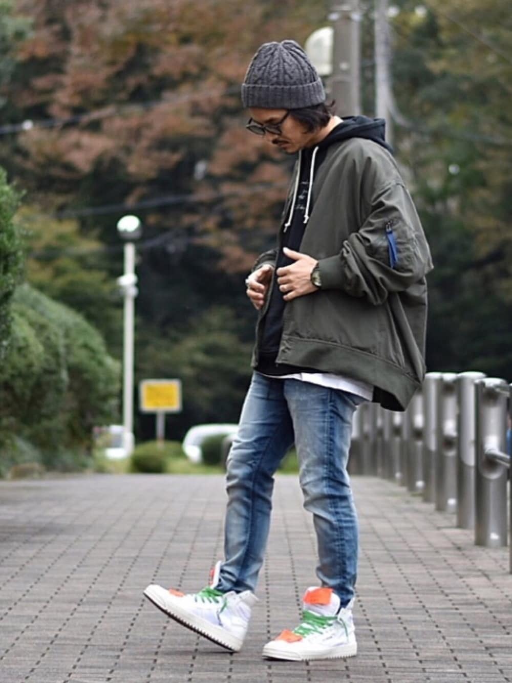 ブラック系のパーカー、ブルー系のデニムパンツ、ホワイト系のスニーカーを着用したメンズの冬コーディネートの1枚目の写真