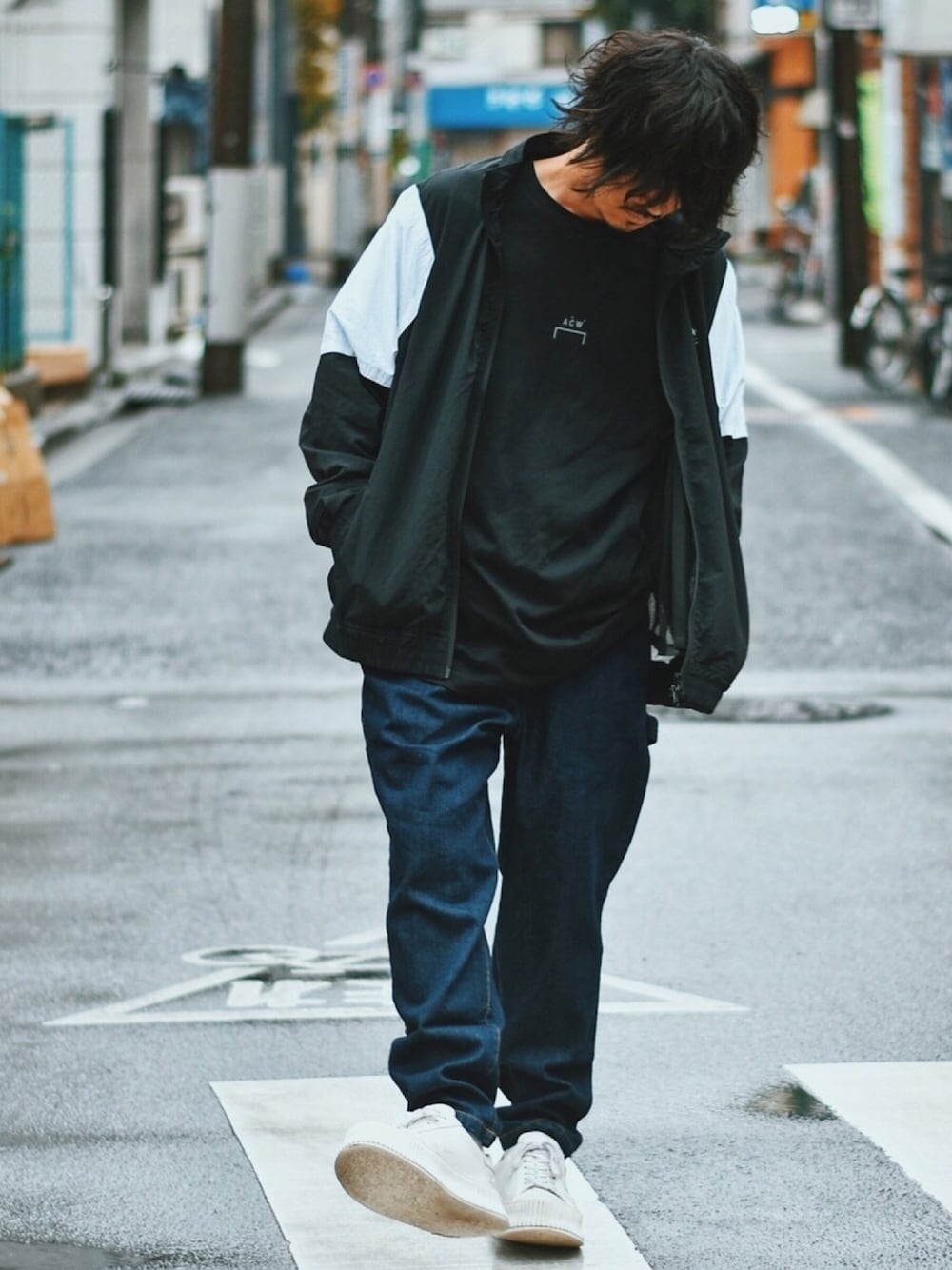 ブラック系のナイロンジャケット、ブラック系のTシャツ/カットソー、ブルー系のデニムパンツを着用したメンズの秋コーディネートの1枚目の写真