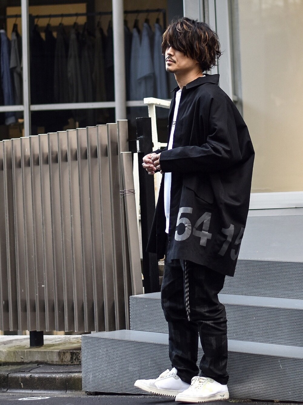 ブラック系のステンカラーコート、ホワイト系のスウェット、ブラック系のデニムパンツを着用したメンズの冬コーディネートの1枚目の写真