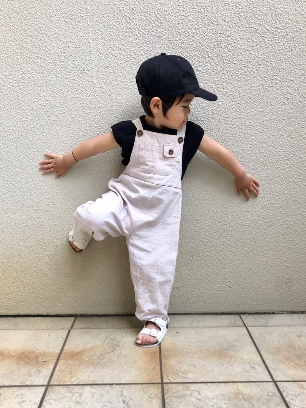 ブラック系のTシャツ/カットソー、ホワイト系のサロペット/オーバーオール、ホワイト系のサンダルを着用したキッズの春コーディネートの1枚目の写真